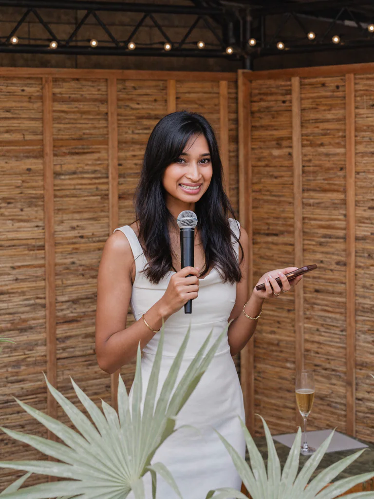 Rushmi, Melbourne marriage celebrant, holding a microphone at an outdoor ceremony.